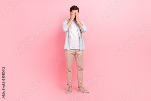 Full body photo of handsome young guy hiding face crying sadness dressed stylish blue clothes isolated on pink color background