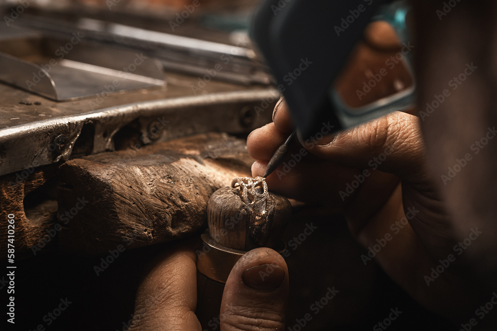 Close up of a goldsmith's hand making a gold or silver ring or a diamond using goldsmith's tools. Making ring with diamonds