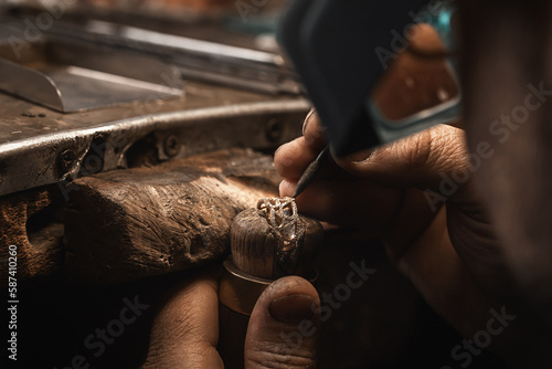 Close up of a goldsmith's hand making a gold or silver ring or a diamond using goldsmith's tools. Making ring with diamonds © svitlychnaja