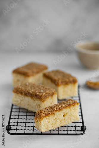 Danish Dream Cake Drømmekage. Sponge cake with coconut and brown sugar topping on a light background.