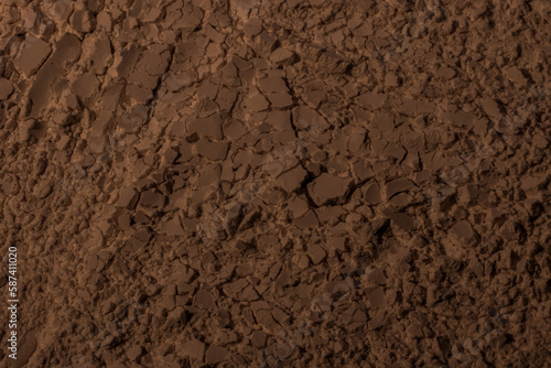 Texture of clay, sand, earth. Brown. Background. Cracked, cracks, waves, mountains, circles, hollows. dented