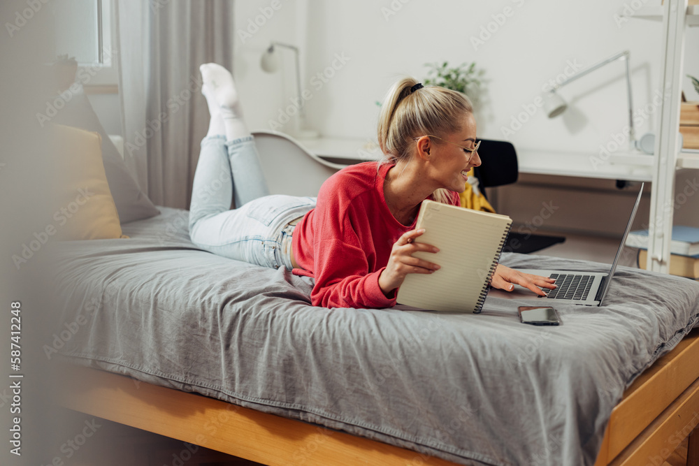 A cute caucasian woman is studying on the bed