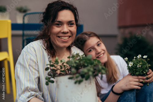 Portrait of a happy mother with her daughter in the yard planting pants together