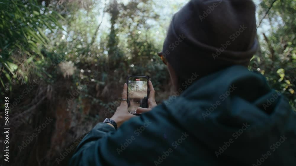 Female tourist taking photos of beautiful abandoned railway tunnel in national park with smartphone during hike. Rack focus, back view Female tourist taking photos of beautiful abandoned railway tunnel in national park with smartphone during hike. Rack focus, back view