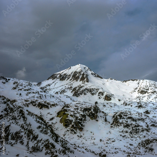 Snow covered Muratov peak summit in winter cloudy day. Winter mountains in Pirin national park near Bansko, Bulgaria.