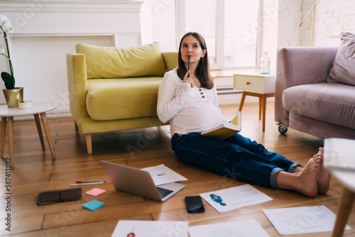 Pregnant woman thinking of new project ideas on floor © BullRun