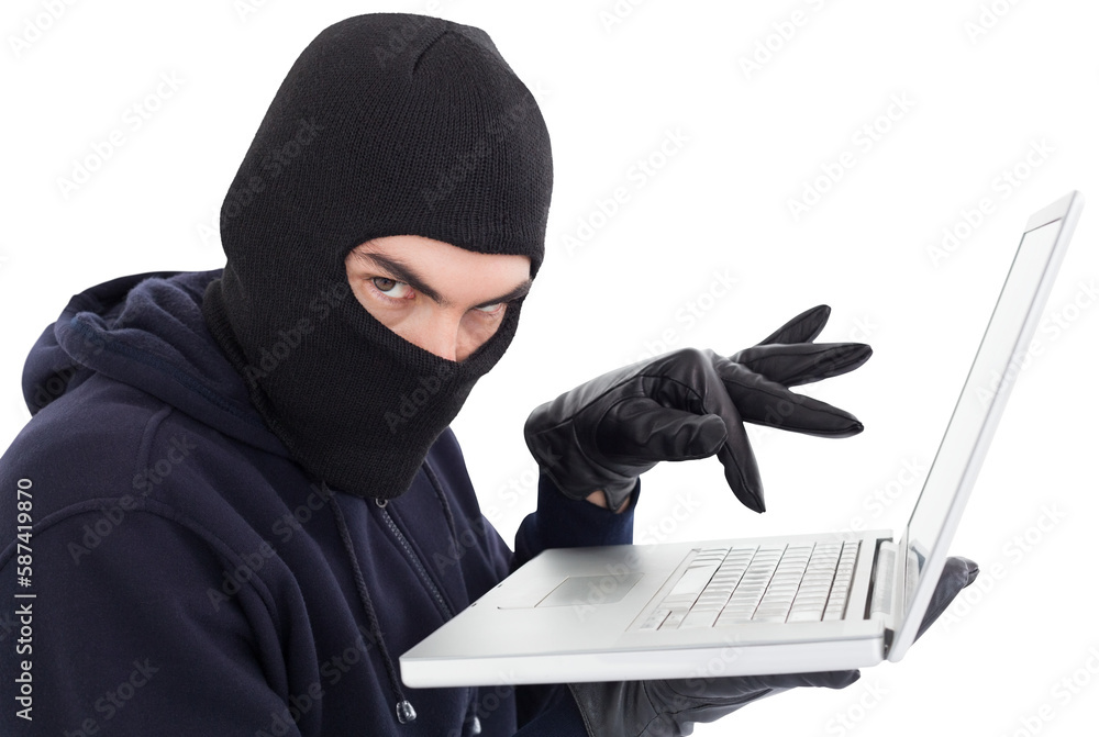 Hacker in balaclava standing and typing on laptop Hacker in balaclava standing and typing on laptop