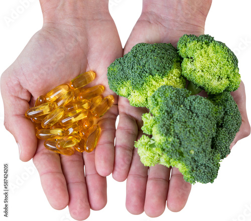 Cropped hands holding broccoli and vitamin pills
