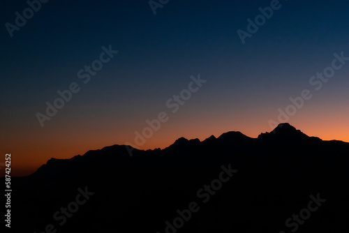 Black silhouette of mountains against the sky during sunset.