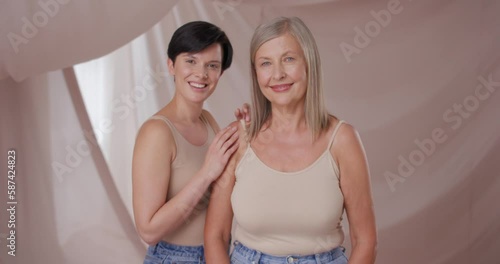 Portrait shot of charming women looking straight to camera, smiling, hugging, glancing. Pretty happy friends, feeling cheerfulness, energy. Body rejuvenation, healthy, theatment concept. photo
