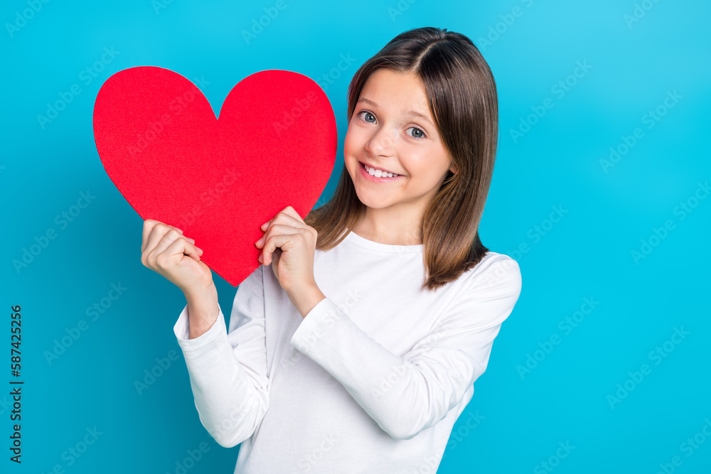 Photo of pleasant cute schoolgirl with straight hairdo dressed white shirt demonstrate red heart isolated on blue color background Photo of pleasant cute schoolgirl with straight hairdo dressed white shirt demonstrate red heart isolated on blue color background