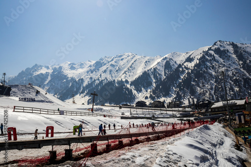 Almaty Kazakhstan 25 March 2023. Medeo Shymbulak Mountain Resort's ski slopee with skiers and snowboarders. Skiers at slopes of ski resort Chimbulak.  photo