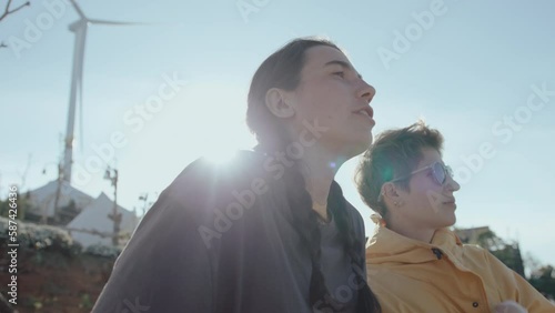 Two female tourists standing on the viewpoint at glampsite, discussing mountain scenery, enjoying weekend getaway in nature photo