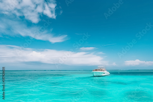 Motor boat in turquoise ocean water against blue sky with white clouds and tropical island. Summer vacation, tropical beach with turquoise water, summer holidays vacation. generative ai