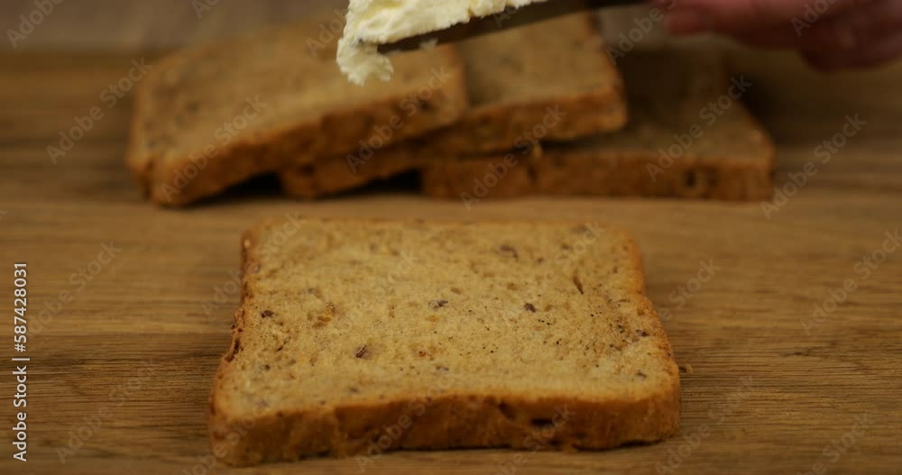 Cream cheese spread with a knife on a piece of multigrain bread on a wooden cutting board. Cream cheese spread with a knife on a piece of multigrain bread on a wooden cutting board.