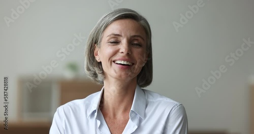 Head shot happy attractive businesslady staring at cam pose indoors. Portrait of mature woman having beautiful european appearance, positive mood, look at camera revealing wide toothy perfect smile photo