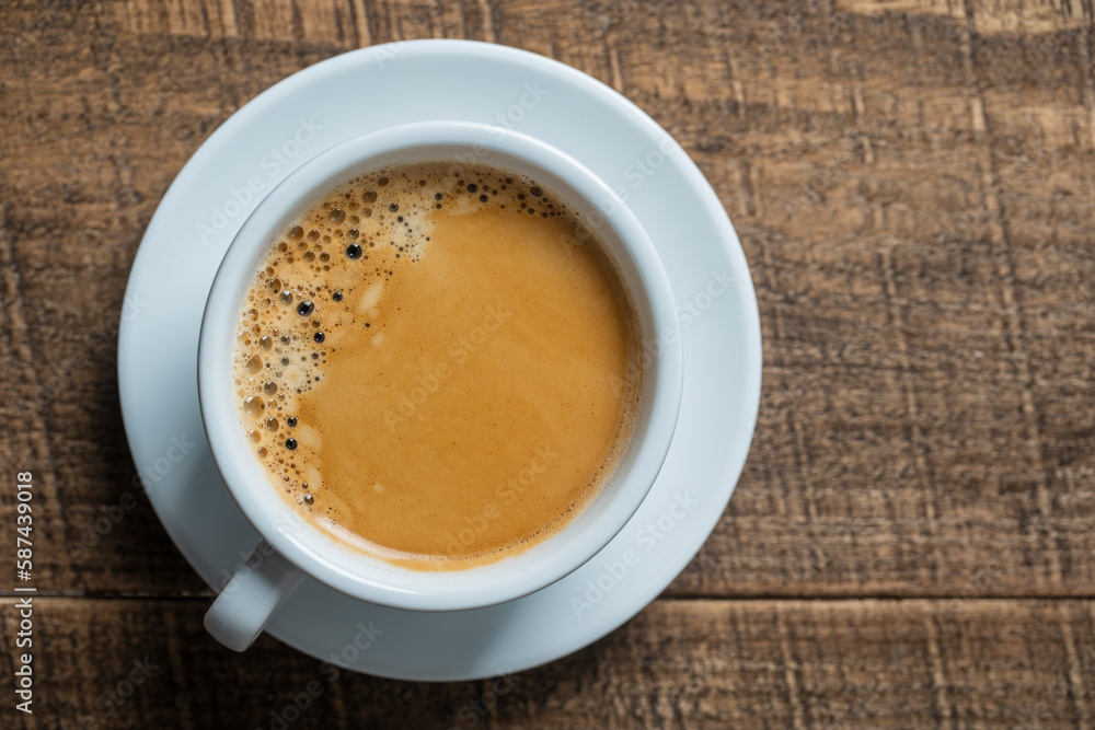 White porcelain coffee cup with saucer over wooden background, top view, copy space, closeup. Hot coffee in a breakfast White porcelain coffee cup with saucer over wooden background, top view, copy space, closeup. Hot coffee in a breakfast