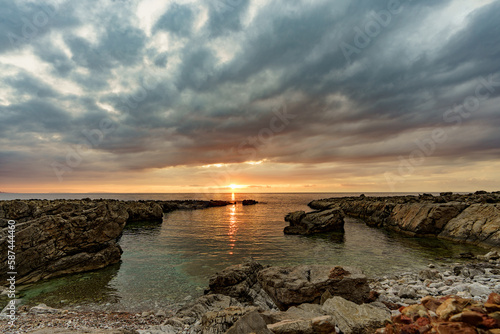 Beautiful sunset on a glass beach by the sea surrounding Sicily and its rocky shores.