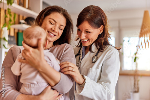 A smiling female pediatrician meeting with a newborn baby on a home visit.