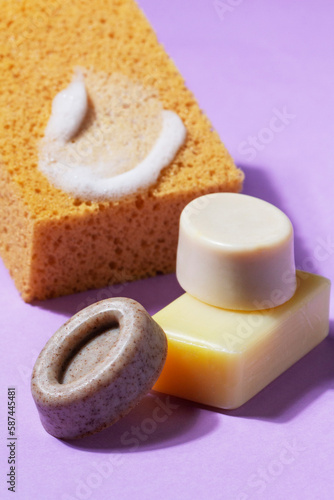 Obraz na płótnie Handmade soap with the addition of coffee and wild herbs and a sponge with foam on a purple background. w salonie