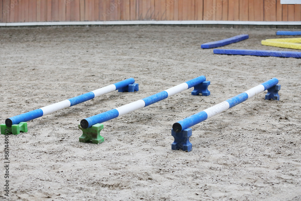 Horse obstacle course outdoors summertime. Poles in the sand at equestrian center indoors