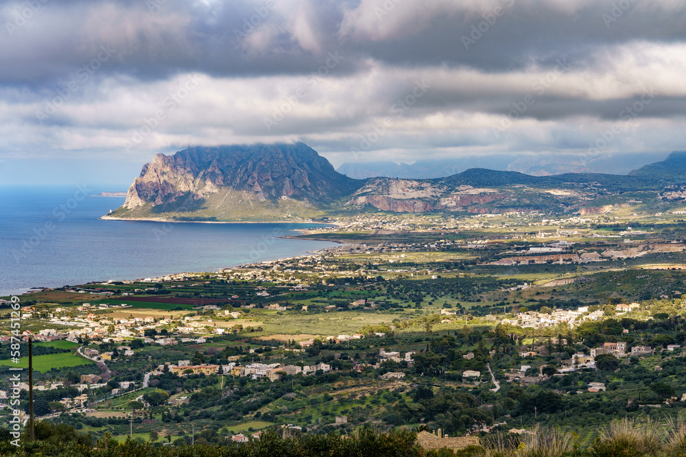 A beautiful seaside mountain covered with a dark rainy cloud below with a town.