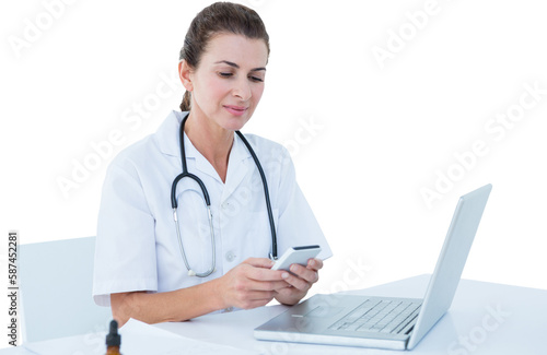 Female doctor using mobile phone with laptop on table