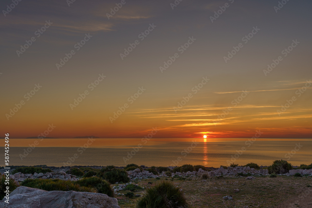 Obraz premium Beautiful sunset on a glass beach by the sea surrounding Sicily and its rocky shores.