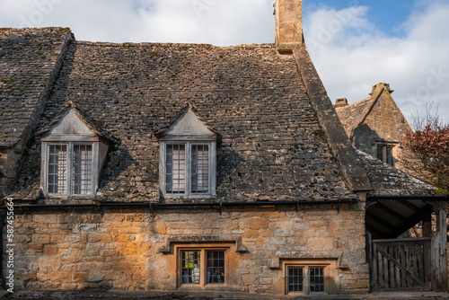 Detail of old traditional windows and roof tiles of stone built cottages in Cotswolds England