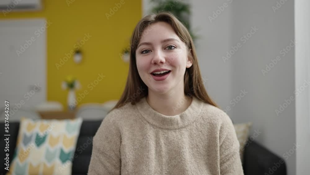 Young blonde woman having video call sitting on sofa at home Young blonde woman having video call sitting on sofa at home