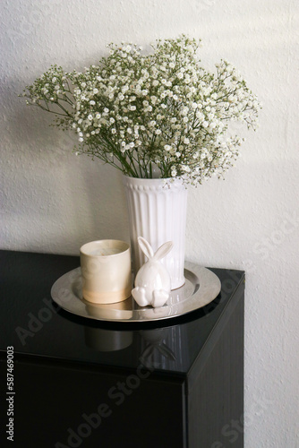 Upper view of a vase with gypsophila flowers on a table with easter ceramic bunny and a candle.  © TatjanaMeininger