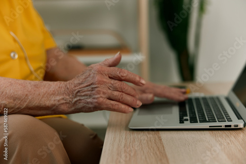 Cookie elderly woman typing on a modern laptop text close-up hands with a keyboard, online chatting.