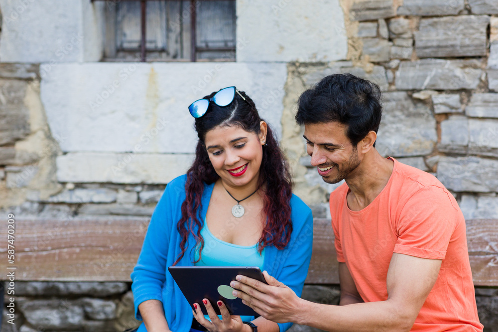mixed race couple together in Villanueva Asturias using tablet technology outdoors on holyday mixed race couple together in Villanueva Asturias using tablet technology outdoors on holyday