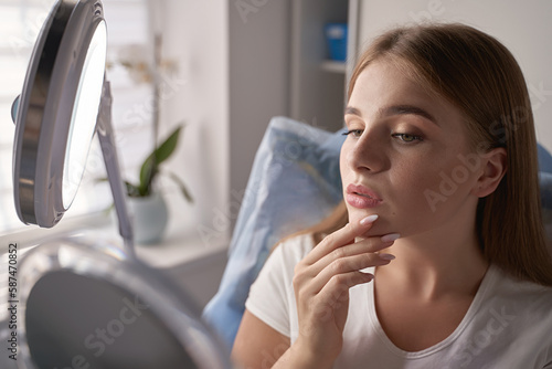 Obraz na płótnie Young beautiful woman customer with mirror getting ready for beauty procedures in a medical salon w salonie