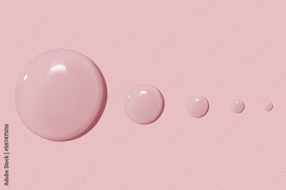 large drops of cosmetic serum, liquid, water, gel on a pink background large drops of cosmetic serum, liquid, water, gel on a pink background