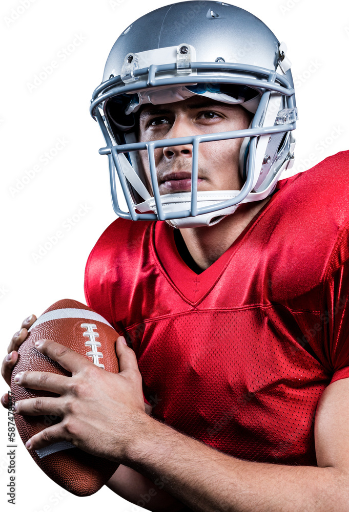 Serious American football player looking away while holding ball Serious American football player looking away while holding ball