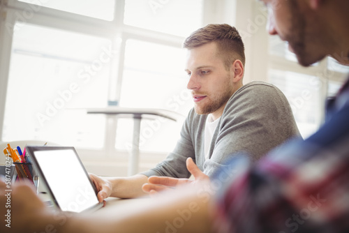 Coworkers discussing over digital tablet
