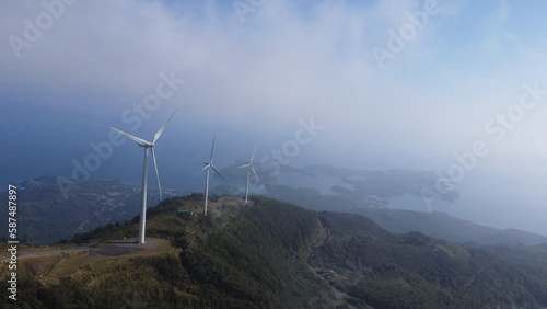Windmills. Windmill farm. Wind turbines on top of a mountain among the clouds.