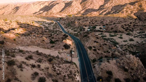 Aerial drone footage of a single white vehicle car driving on the road to Pioneertown, California.  photo