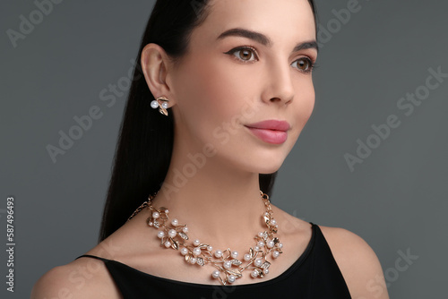 Beautiful young woman with elegant jewelry on dark grey background