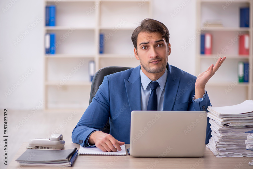 Young male employee and too much work in the office Young male employee and too much work in the office