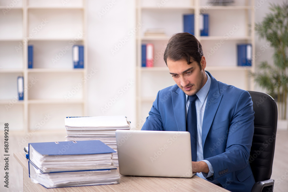 Young male employee and too much work in the office Young male employee and too much work in the office