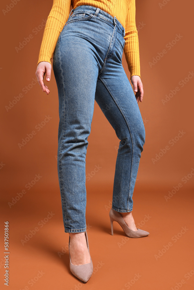 Woman in stylish jeans on brown background, closeup Woman in stylish jeans on brown background, closeup