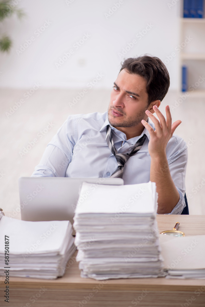 Naklejka premium Young male employee and too much work in the office