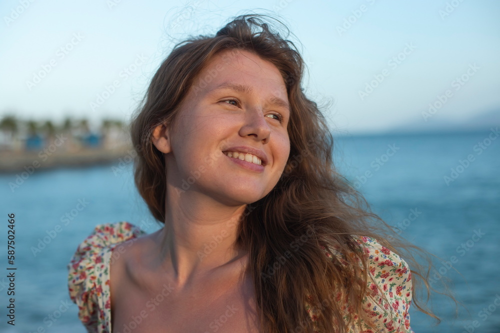 young feminine girl in a dress stands on promenade by sea and enjoys a warm summer day young feminine girl in a dress stands on promenade by sea and enjoys a warm summer day