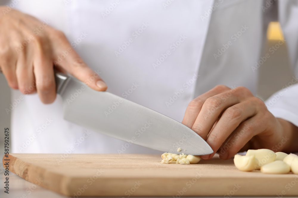 Professional chef cutting garlic at white marble table indoors, closeup Professional chef cutting garlic at white marble table indoors, closeup