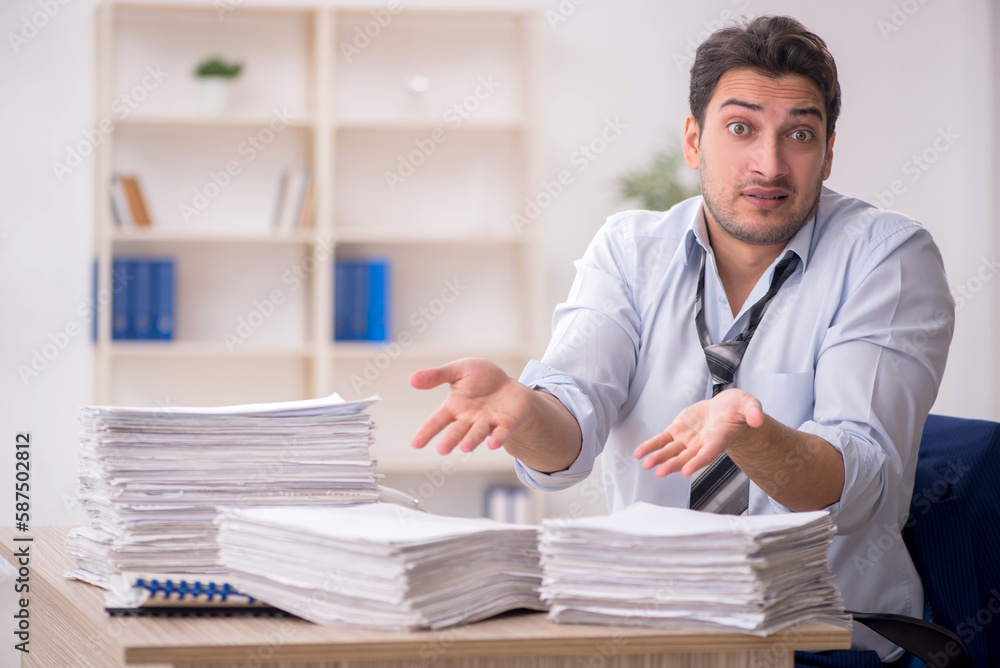 Young male employee and too much work in the office Young male employee and too much work in the office