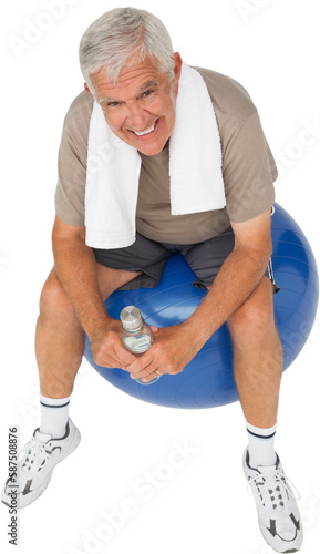 Happy senior man with water bottle sitting on fitness ball