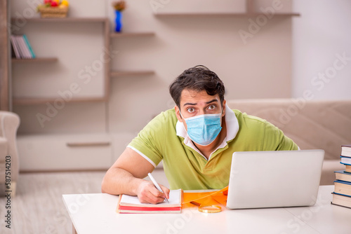 Young male student preparing for exams at home during pandemic