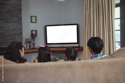 Rear view of family watching television while sitting on sofa